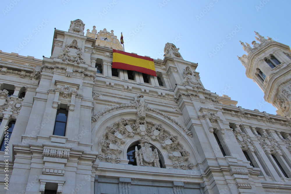 Close up on Cybele Palace (Centrocentro building) with Spain flag, in Madrid, capital city of Spain.
