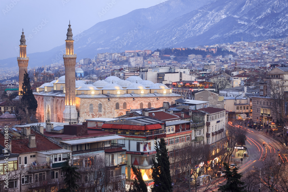 Historical Grand Mosque (Ulucami), Uludag in winter and Bursa city night landscape at blue hour.