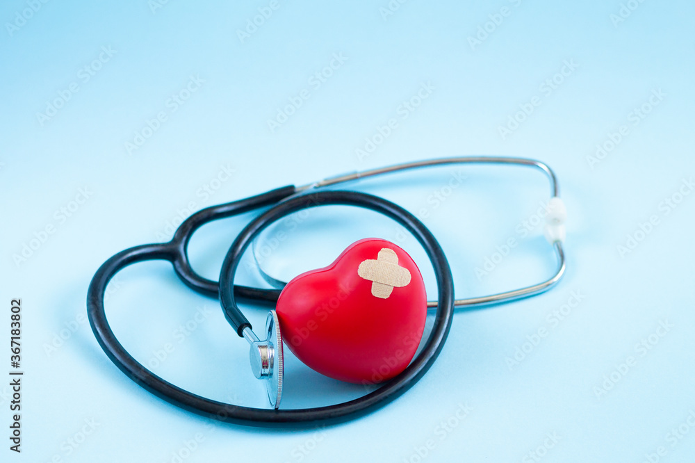 Medical stethoscope and red heart with patch isolated on blue background Medical stethoscope and red heart with patch isolated on blue background