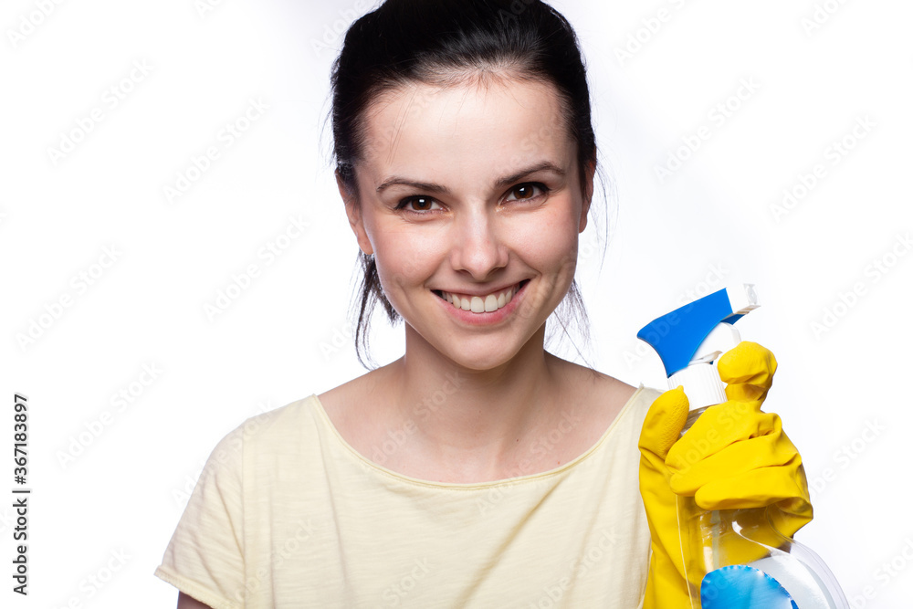 woman in orange uboki gloves holds a spray bottle with liquid for washing glass, light background woman in orange uboki gloves holds a spray bottle with liquid for washing glass, light background