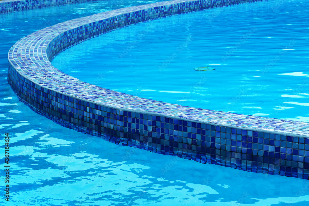 blue clear water in the summer pool with blue mosaic tiles.  summer vacation