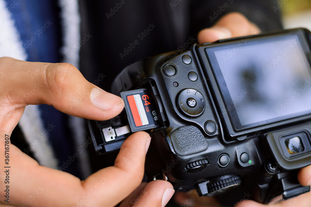 Inserting high-capacity memory card into photo camera outdoors Inserting high-capacity memory card into photo camera outdoors