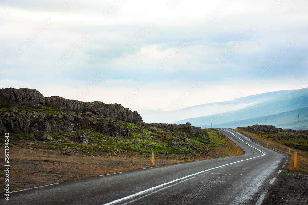 a winding road leads to the misty hills, nature of Iceland