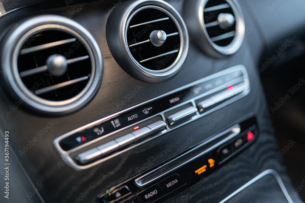 Naklejka premium The center panel of the car interior with a view of the radio, air conditioning and other switches that make driving an elegant car more enjoyable.