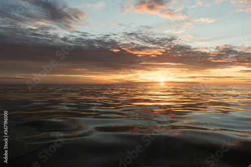 Beautiful sunset on the calm sea. Colorful sky and clouds. Scenic evening landscape - view from the boat. 