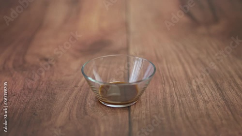 A glass bowl with worcestershire sauce on a wooden brown table in 4K.