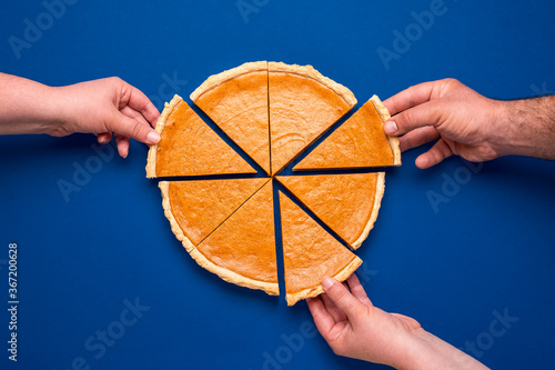 Sliced pumpkin pie above view on blue background. People grabbing slices of cake photo