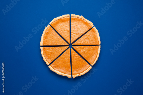 Sliced pumpkin pie top view isolated on classic blue background. Homemade cake.