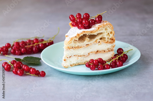 A piece of choux pastry with cheese cream, garnished with red currants. Karpatka cake.