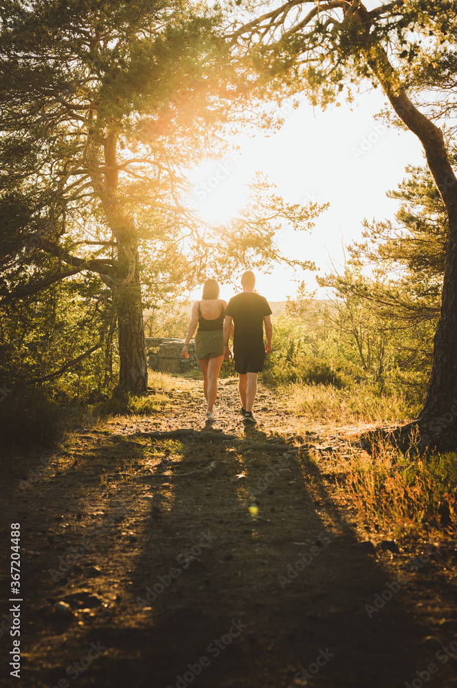 Couple walking in a park towards the sun Couple walking in a park towards the sun