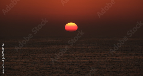 Sun disappearing below horizon at sunset on the ocean