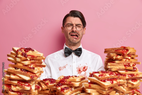 Fotografie Displeased crying man has dirty white shirt as ate bread snack not carefully, ex