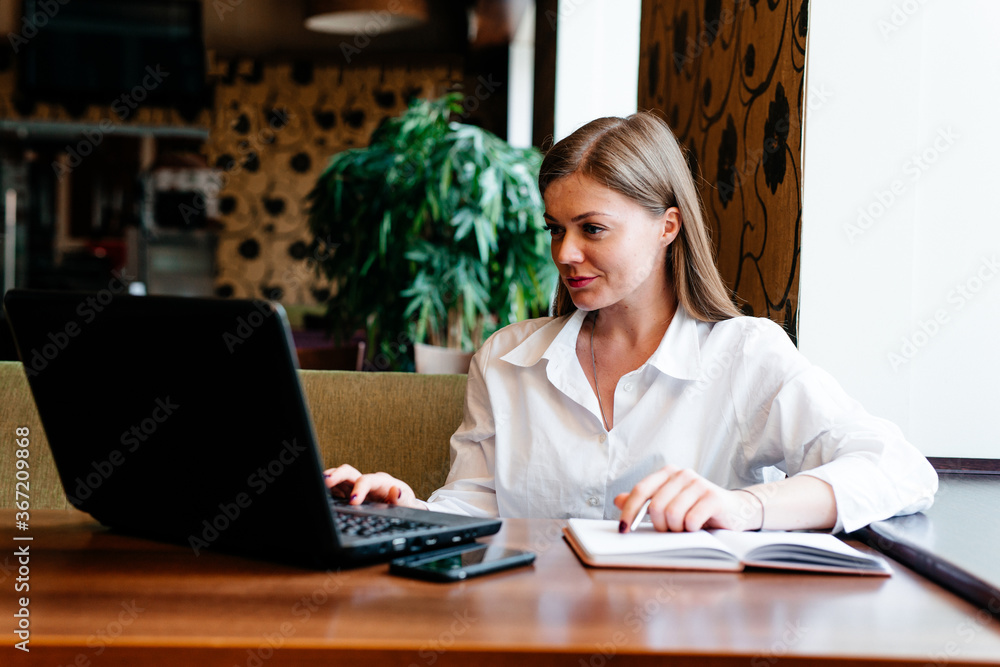 Young woman working on the laptop sitting in the cafe Young woman working on the laptop sitting in the cafe