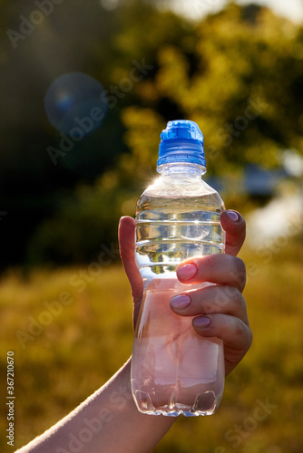 Woman's hand with a plastic bottle of clean fresh transparent water.