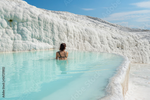 Woman in sunglasses bathing in travertine terraces pools in Pamukkale, Turkey photo