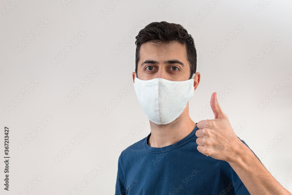 Young man making ok sign while wearing a mask to cover his mouth and nose to have protection from the world coronavirus covid19 pandemic