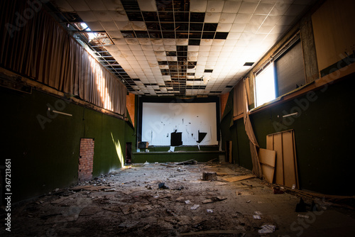 Abandoned and damaged interior of a movie theatre with stage.