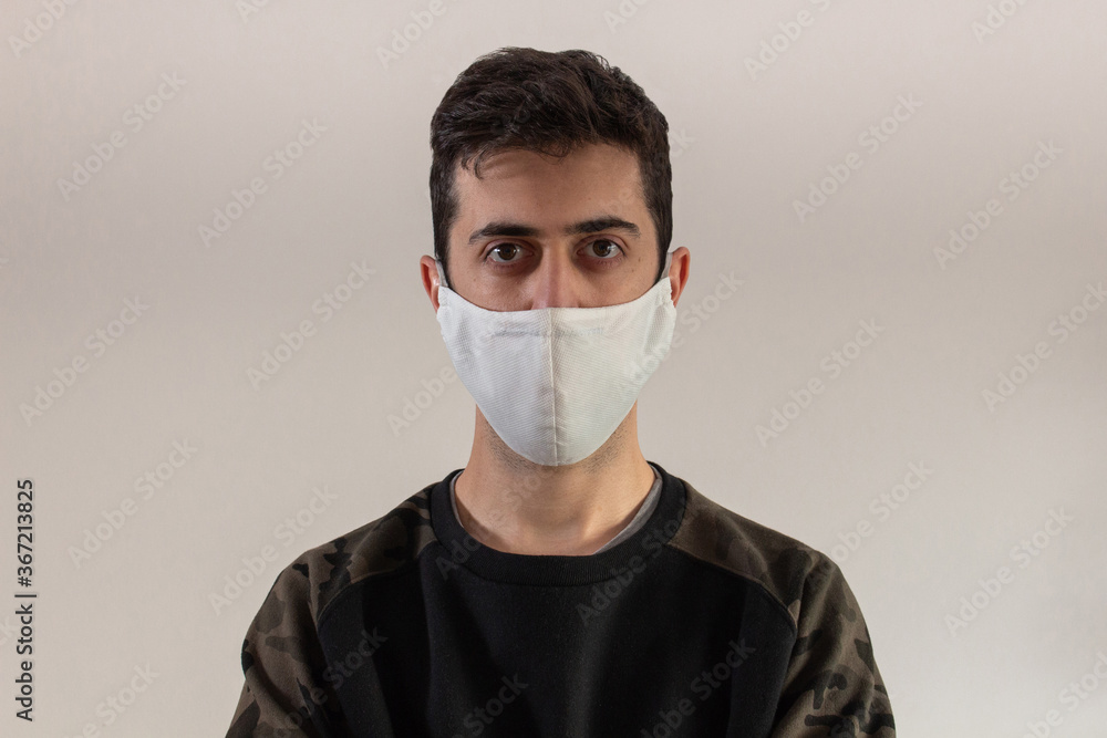 Young man using a mask to cover his mouth and protect himself from the coronavirus pandemic Young man using a mask to cover his mouth and protect himself from the coronavirus pandemic