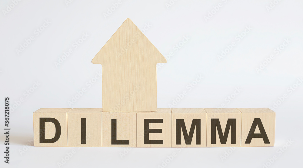 Wooden blocks with the word DILEMMA , house. The concept of the high cost of rent for an apartment or home. Interest rates are rising. Real estate market. Wooden blocks with the word DILEMMA , house. The concept of the high cost of rent for an apartment or home. Interest rates are rising. Real estate market.