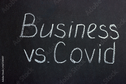  The inscription on the chalk board "Business versus covid". The slogan of modern reality