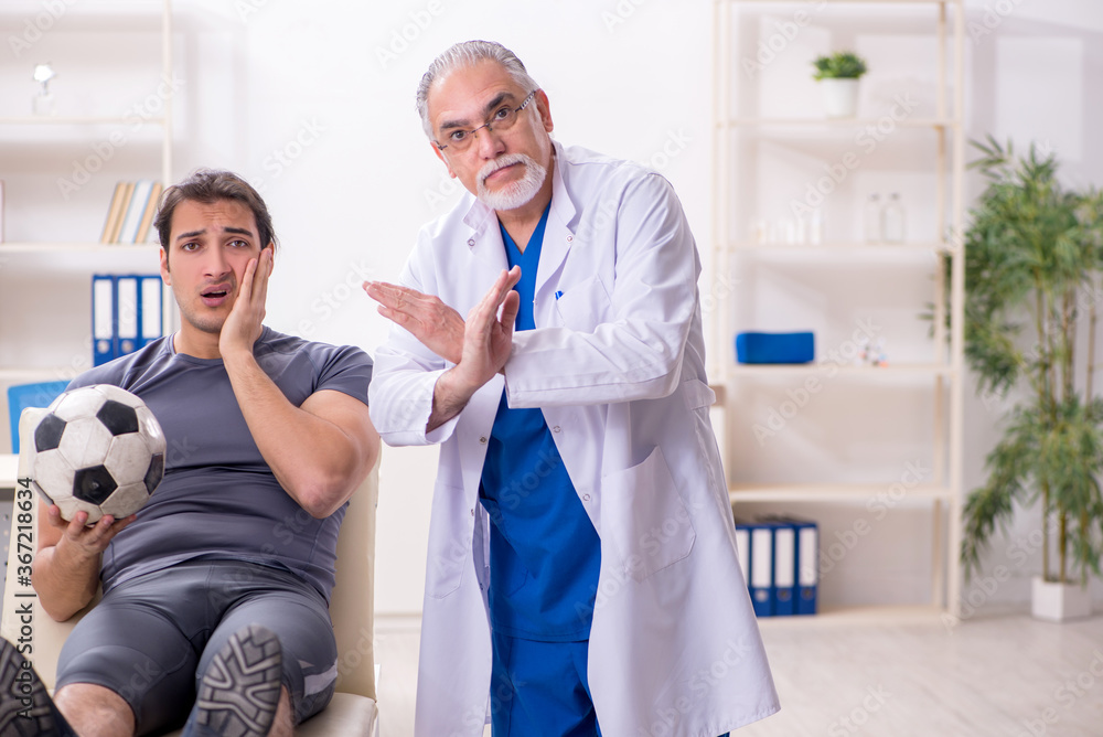 Fototapeta premium Young injured soccer player visiting old doctor traumatologist
