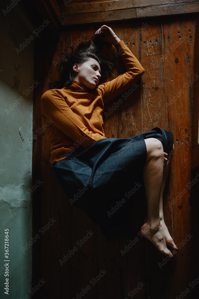 Girl in deep depression lies on a wooden floor in a room at home