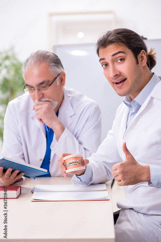 Experienced doctor dentist teaching young male assistant Experienced doctor dentist teaching young male assistant