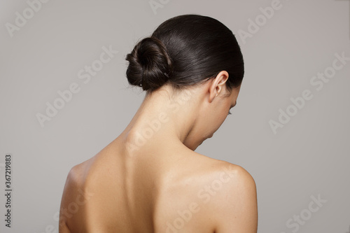 brunette with a smooth bun hairstyle from the back. on gray background photo