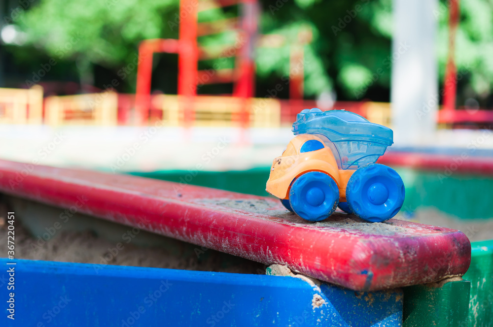 Children's playground with empty sandbox and abandoned colorful toy car. Relaxation park, leisure place for families and children. Coronavirus. Quarantine, kids are at home.