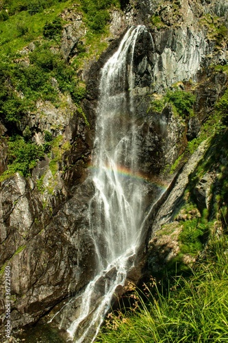 Top view of a beautiful waterfall on the mountain rock on a sunny summer day with a rainbow.