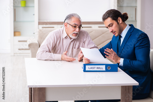 Young male lawyer visiting old man in testament concept photo