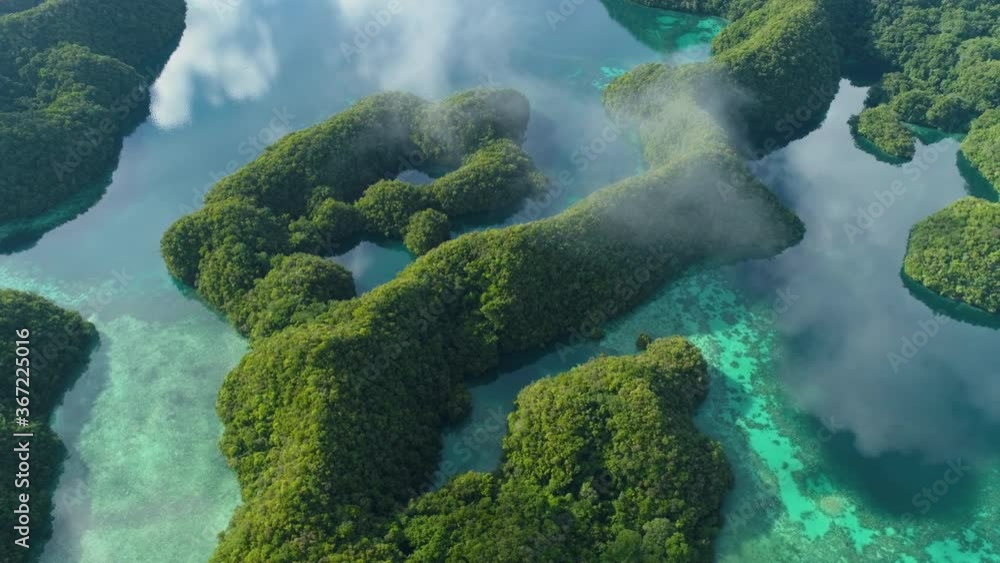 Aerial shot flying over rock islands of Palau with calm reflective water Aerial shot flying over rock islands of Palau with calm reflective water