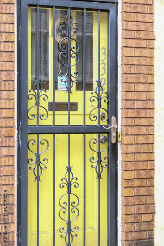 Yellow door behind a metal storm door