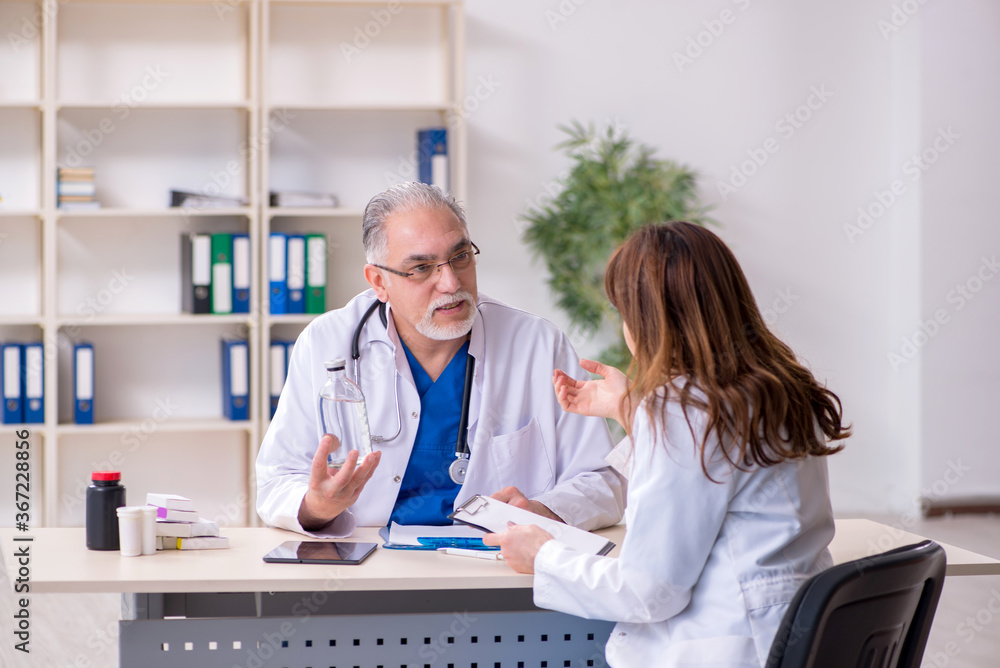 Old male doctor and his young female assistant in the clinic