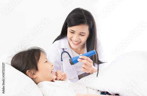 asian female doctor use hand open mouth of children, she use flashlight and diagnosis in hospital, children show her tongue, child clinical screening, happiness hospital