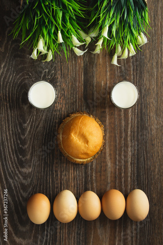 Indifference is an emotion, a hamburger bun lies on a section of a tree trunk and a glass of milk with brown eggs against a background of textured wood and flowers.