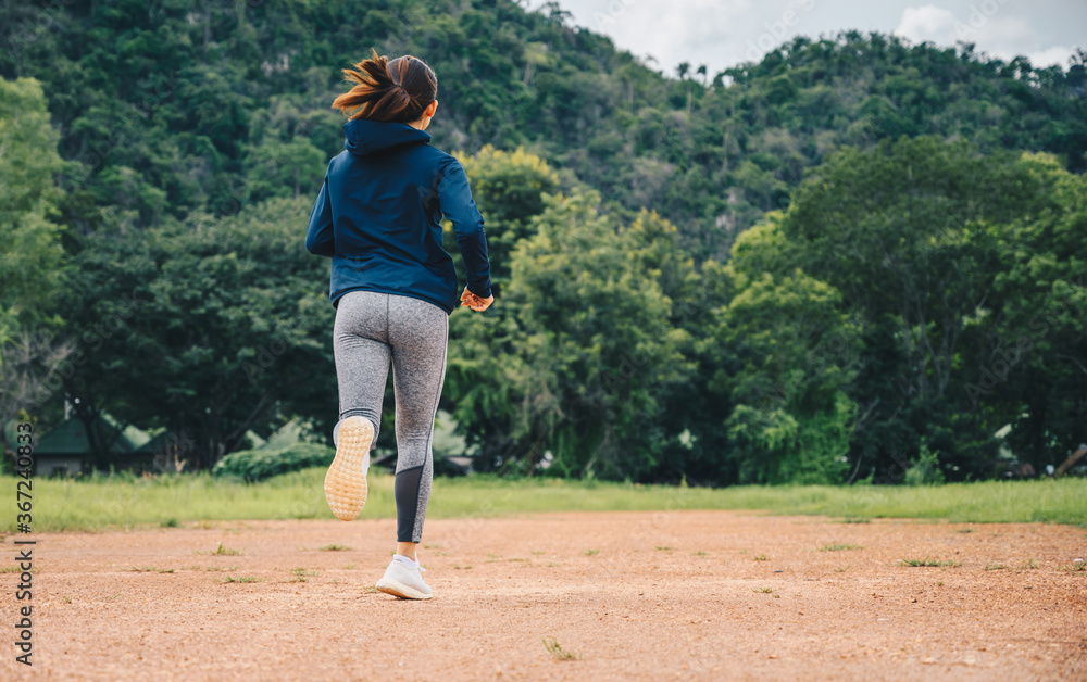 Obraz premium Woman doing workout by running on dirt road (or Trail running). The benefit when running on dirt road can reduce impact on the joints and pushes your muscles in a variety of challenging ways.