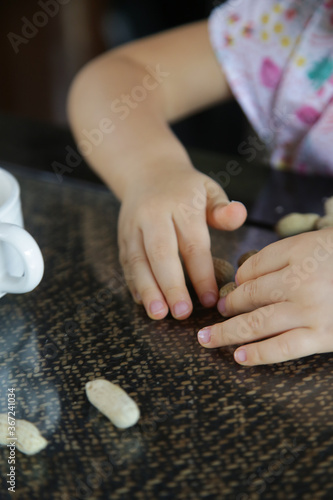 Top view of child's hands and peanuts in shell on the kitchen table