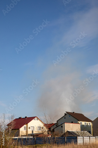 ZYMNA VODA, UKRAINE - APRIL 10, 2020: dark smoke air pollution in ukrainian village with blue sky background