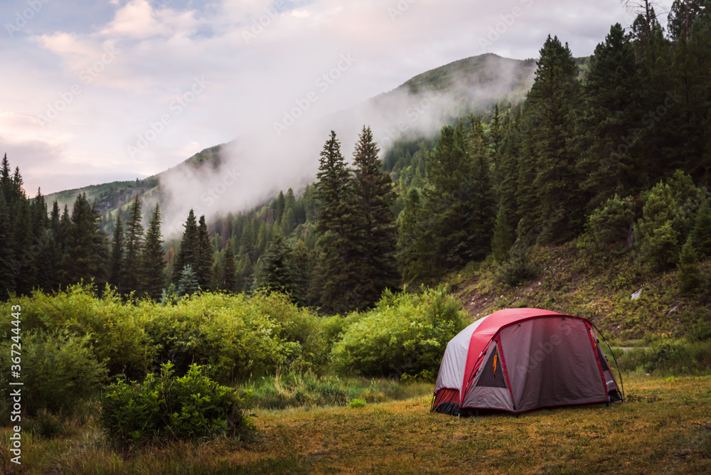 A tent set up in the mountains during sunset. 