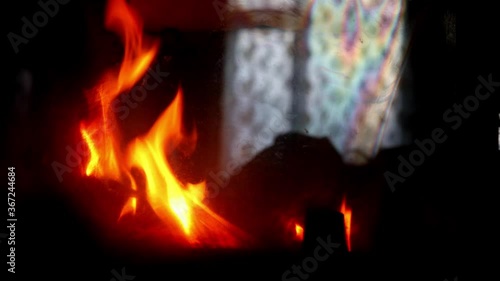 Bright orange fire flames and wooden log in fireplace at home with dark background