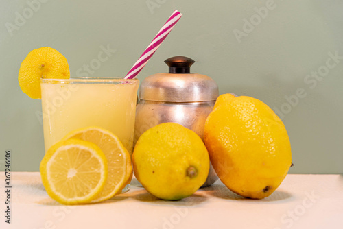 Refreshing drink of lemonade and lemons on green background