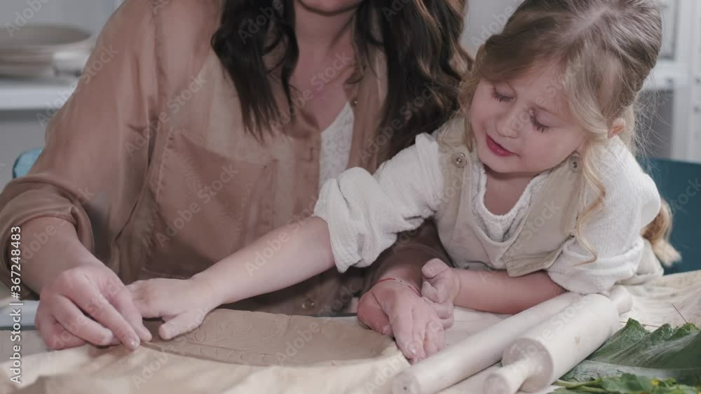 Woman and girl kneading clay. Family make art product at table in pottery workshop. Mother with daughter. Woman and girl kneading clay. Family make art product at table in pottery workshop. Mother with daughter.