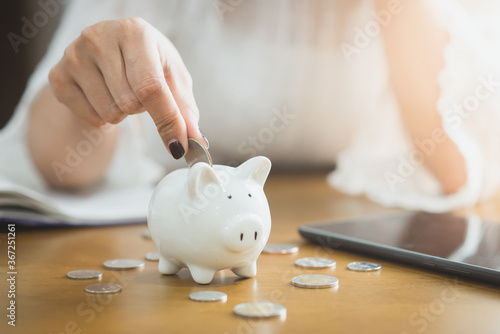 Woman inserts a coin into a piggy bank, financial concept photo