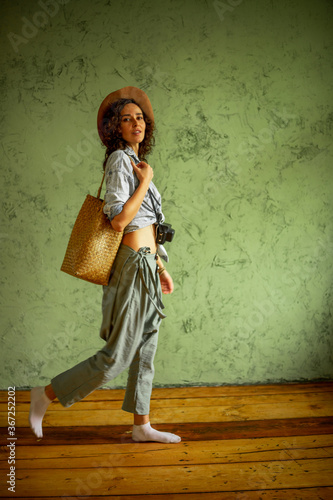 Tourist in a denim jacket and hat with a camera and bag. Happy emotions
