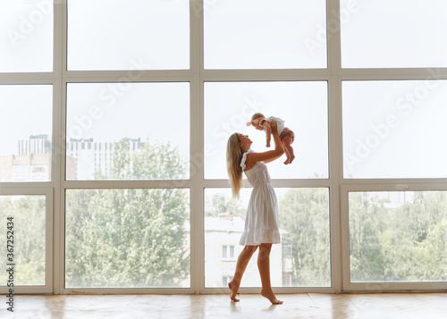 girl raise her daughter up by the window