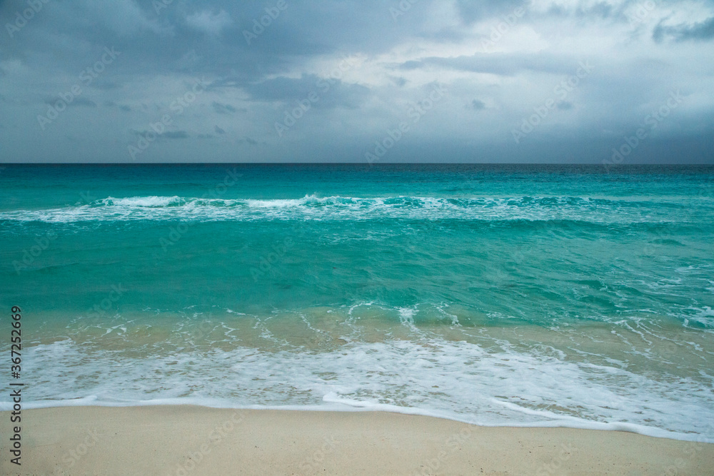 Paradise. Seascape. Turquoise color  water sea. The white sand and ocean waves under an enchanting cloudy sky in Cancun, Mexico. 