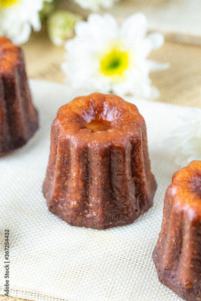 Caneles cake, French sweet dessert with white flowers serve with tea or coffee. Selective focus. Caneles cake, French sweet dessert with white flowers serve with tea or coffee. Selective focus.