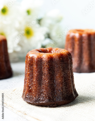 Caneles cake, French sweet dessert with white flowers serve with tea or coffee. Selective focus.