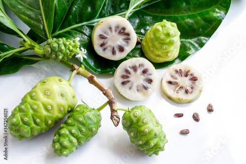 Noni fruit or Morinda Citrifolia and noni slice with seed and green leaves of the noni isolated on white background.